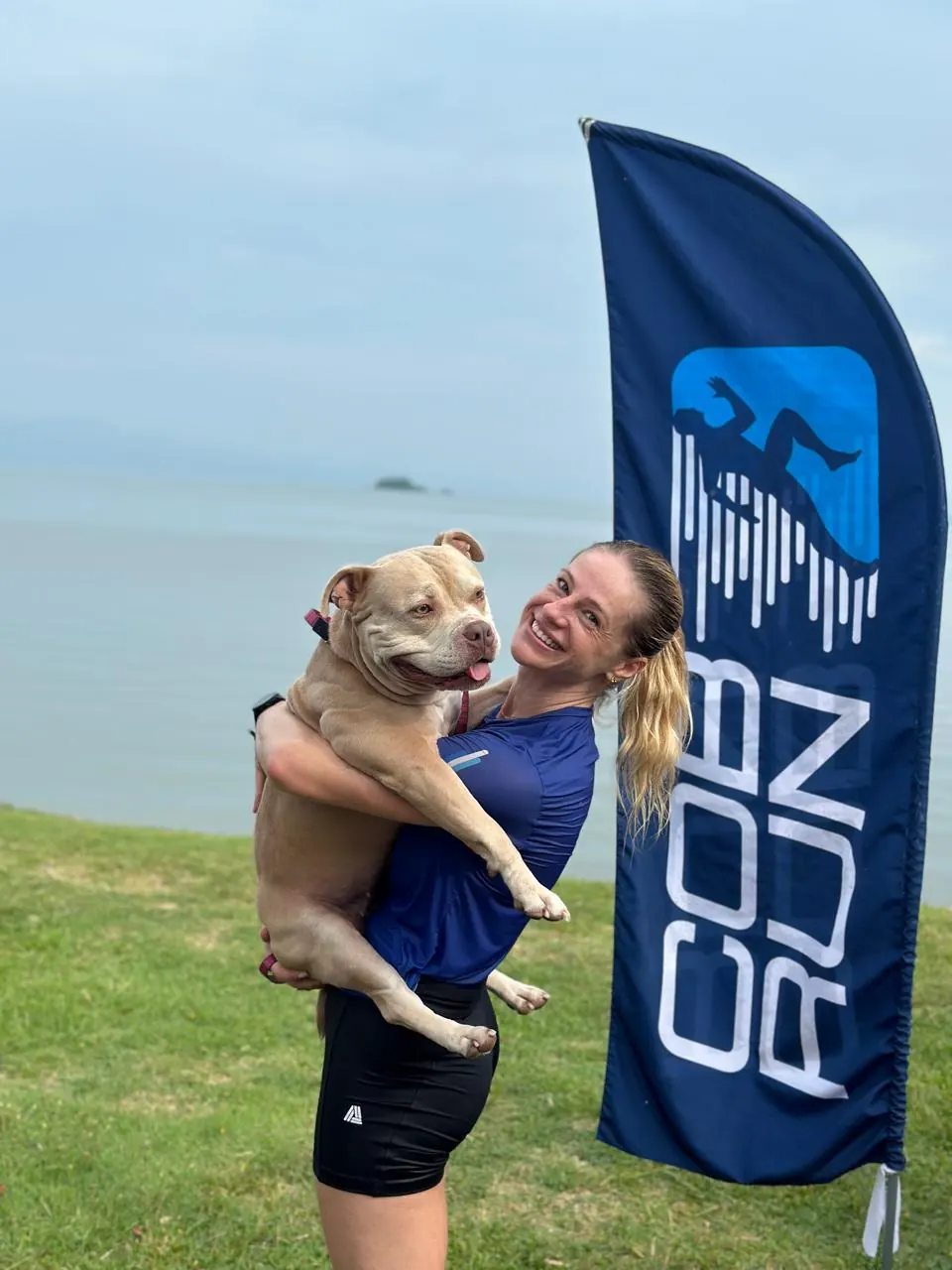 Atleta da COB Run com seu cão ao lado da bandeira da equipe