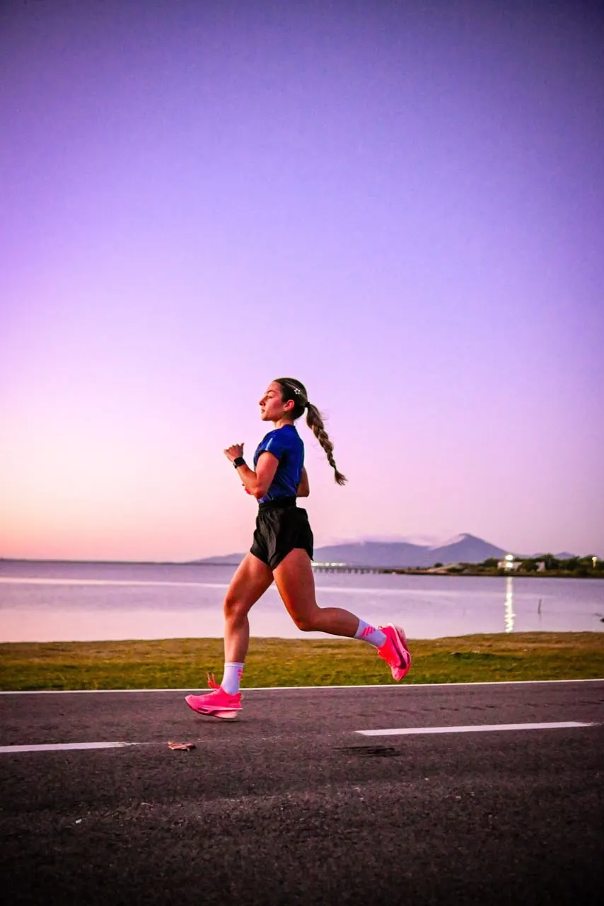 Atleta da COB Run correndo na orla ao entardecer